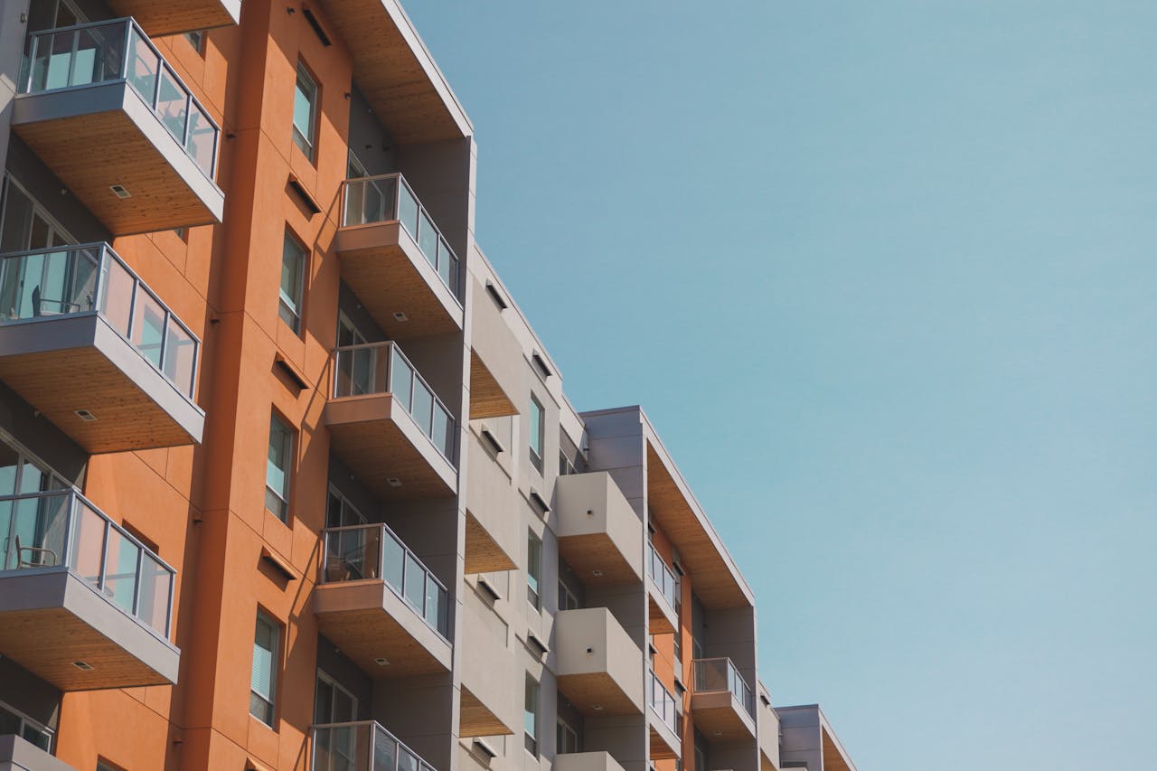 portfolio-03 Contemporary apartment building with glass balconies under a clear blue sky.